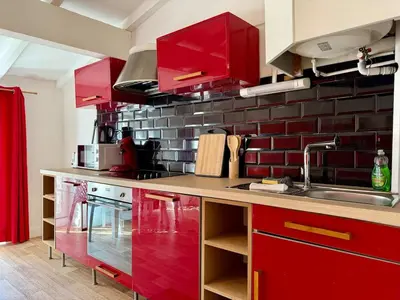 a kitchen with red cabinets and a sink at L'Etoile Rouge - T2 Proche Gare et Centre Ville in Carcassonne