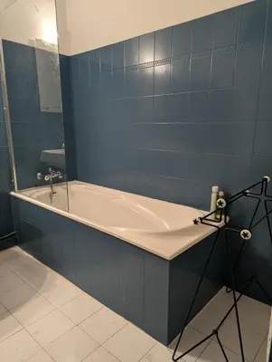 a bath tub in a blue tiled bathroom at Cosy Bastide 4 personnes in Carcassonne