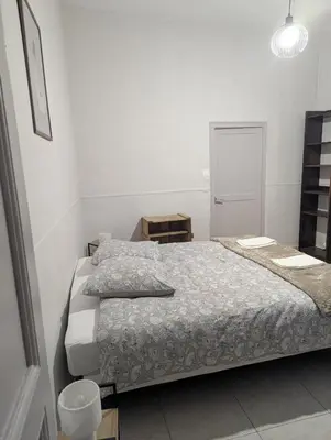 a white bedroom with a bed and a mirror at Cosy Bastide 4 personnes in Carcassonne