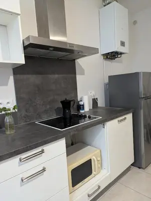 a kitchen with white cabinets and a microwave at Cosy Bastide 4 personnes in Carcassonne