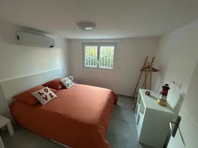 a bedroom with a bed with orange sheets and a window at Appartement 2 chambres proche centre ville avec jardin in Narbonne