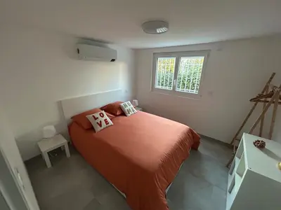 a bedroom with a bed with orange sheets and a window at Appartement 2 chambres proche centre ville avec jardin in Narbonne