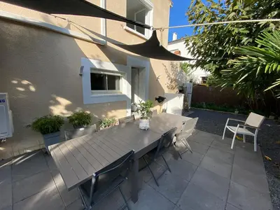 a wooden table and chairs on a patio at Appartement 2 chambres proche centre ville avec jardin in Narbonne