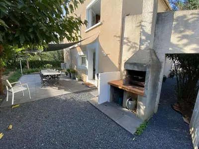 a patio with an outdoor oven next to a house at Appartement 2 chambres proche centre ville avec jardin in Narbonne