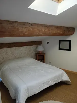 a bedroom with a white bed with a wooden ceiling at Grande maison 7 places in Paziols