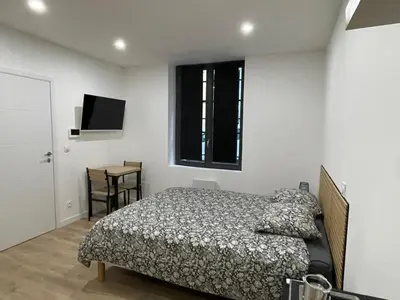 a bedroom with a bed and a table and a window at Studio rénové pour 2 personnes - centre ville in Carcassonne