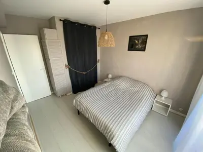 a small bedroom with a striped bed and a window at L'écume d'or T3 in Port-la-Nouvelle