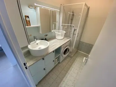a bathroom with a sink and a washing machine at L'écume d'or T3 in Port-la-Nouvelle
