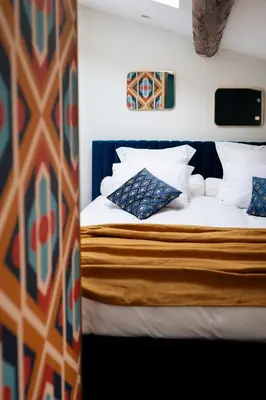 a bedroom with a bed with white sheets and blue pillows at l'écrin du désir in Capestang