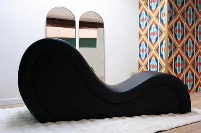 a black chair sitting in a room with a mirror at l'écrin du désir in Capestang