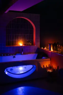 a dark bathroom with a tub and a large window at l'écrin du désir in Capestang