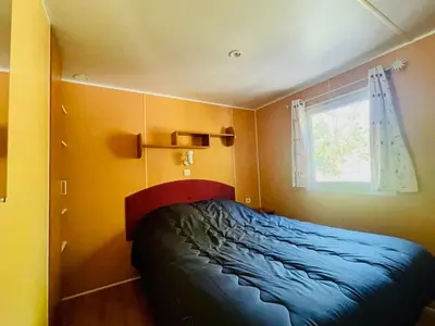 a small bedroom with a bed and a window at Mobil-home confortable avec terrasse au calme - API-1-52-915 in Camon