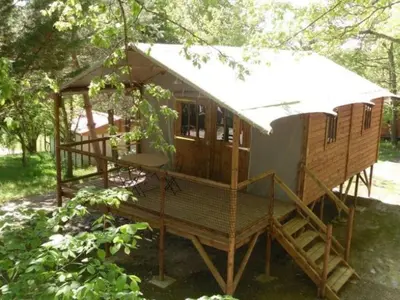 a tiny house in the woods with a porch at Chalet 18m², Terrasse sur Pilotis, 4 Personnes - API-1-52-927 in Camon