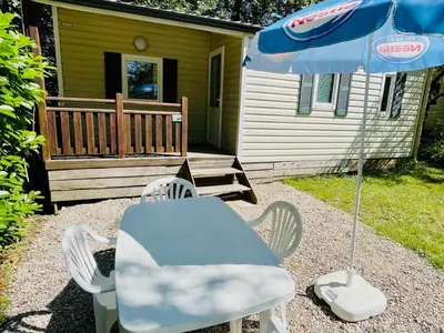 a table and chairs and an umbrella in front of a house at Mobil-home 3 pièces avec terrasse à Camon - API-1-52-1043 in Camon