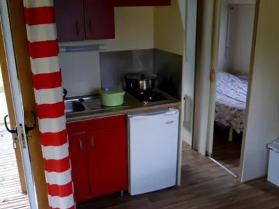 a small kitchen with a stove and a refrigerator at Chalet confortable 4 pers avec terrasse - API-1-52-1139 in Camon