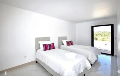 two beds in a white room with a window at Villa Avec Piscine Privée in Portel-des-Corbières