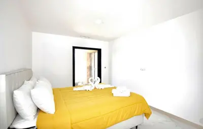 a bedroom with a yellow bed with white pillows at Villa Avec Piscine Privée in Portel-des-Corbières