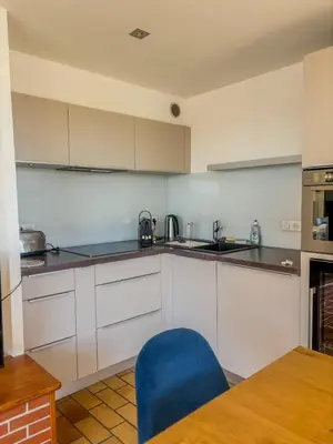 a kitchen with white cabinets and a blue chair at Elégant T3, vue sur le port - Grande terrasse in Gruissan