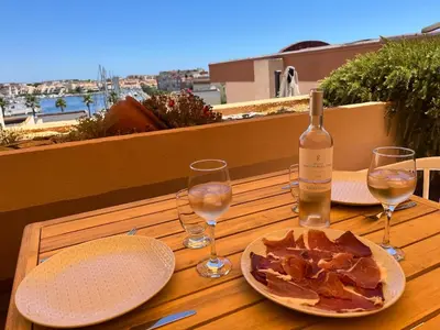a wooden table with a bottle of wine and glasses at Elégant T3, vue sur le port - Grande terrasse in Gruissan