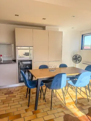 a kitchen with a wooden table and blue chairs at Elégant T3, vue sur le port - Grande terrasse in Gruissan