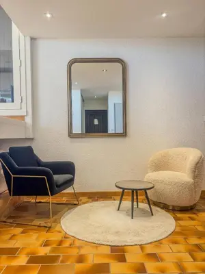 a living room with a mirror and two chairs and a table at Elégant T3, vue sur le port - Grande terrasse in Gruissan
