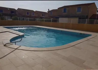 a large swimming pool with blue water in a yard at location maison gruissan in Gruissan