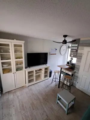 a living room with a flat screen tv and a table at location maison gruissan in Gruissan
