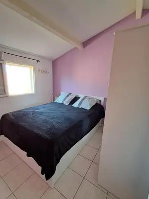 a bedroom with a large bed with purple walls at location maison gruissan in Gruissan