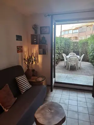 a living room with a couch and a table and a patio at Studio Horizon - Parking Commerces Plage in Port-la-Nouvelle