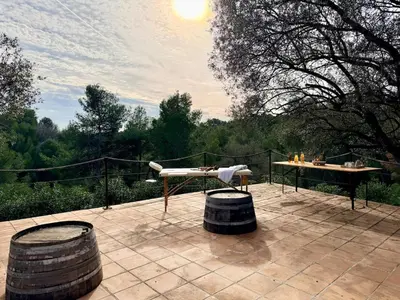 a patio with a table and two barrels on it at Mas Sarava - Retraite détente - Pilates et Massage in Espira-de-lʼAgly