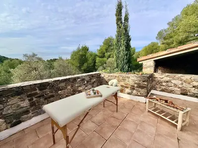 a white table on a patio with a stone wall at Mas Sarava - Retraite détente - Pilates et Massage in Espira-de-lʼAgly