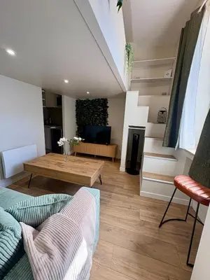 a living room with a couch and a table at Le Jardin, studio façon nature in Castres