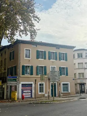 a building with green shuttered windows on a street at Le Jardin, studio façon nature in Castres