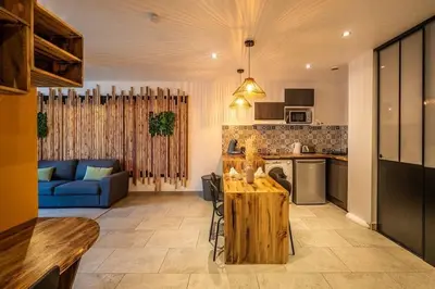 a kitchen and living room with a table and a blue couch at Chez le Golfeur - Cœur & Vignes in Carcassonne