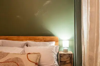 a bedroom with a green wall and a bed with white pillows at Chez le Golfeur - Cœur & Vignes in Carcassonne