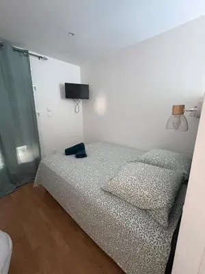 a bedroom with two beds and a television on the wall at Charles de Gaulle lll - Independent Garden in Castres