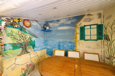 a dining room with a wooden table and a painted wall at La Tomette 3 chambres avec joli patio in Sigean