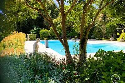 a woman standing next to a swimming pool in a garden at Gîte Le Mississipi in Narbonne