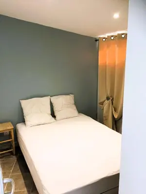 a bedroom with a white bed with a green wall at Gîte Piscine in Narbonne