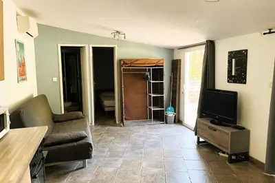 a living room with a couch and a television at Gîte Piscine in Narbonne