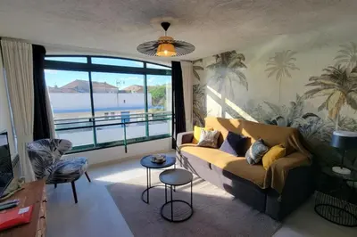 a living room with a couch and a large window at Le Tropical in Port-la-Nouvelle