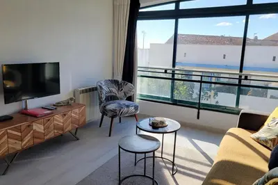 a living room with a couch and a large window at Le Tropical in Port-la-Nouvelle