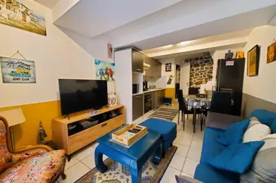 a living room with a blue couch and a tv at L'Occitane Maison de village climatisée in Lapalme