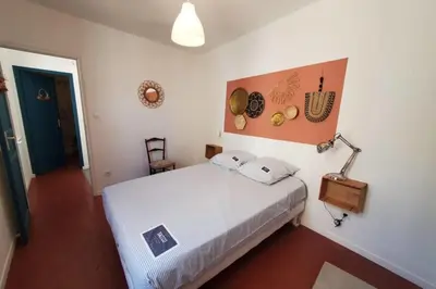 a bedroom with a white bed and a lamp at La Louve in Narbonne