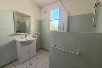 a white bathroom with a sink and a window at L'amandier - Maison avec jardin sans vis à vis in Port-la-Nouvelle