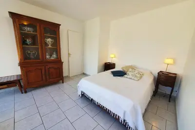 a bedroom with a bed and a wooden cabinet at L'amandier - Maison avec jardin sans vis à vis in Port-la-Nouvelle