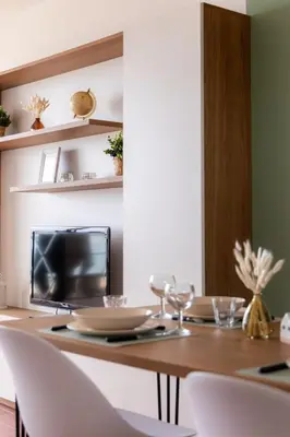a dining room table with white chairs and a television at La Perle de la Mer in Port-la-Nouvelle