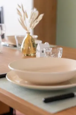 a white plate on a wooden table with a glass at La Perle de la Mer in Port-la-Nouvelle