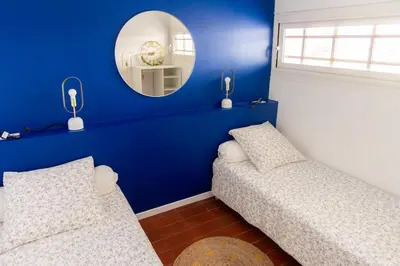 a blue room with two beds and a mirror at La Perle de la Mer in Port-la-Nouvelle