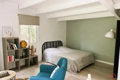 a bedroom with a bed and a blue chair at Gîte Studio Les Ecureuils in Narbonne